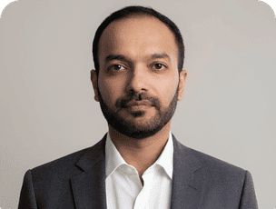 Ankit Joshi in a gray suit and white shirt, professional headshot against a light background
